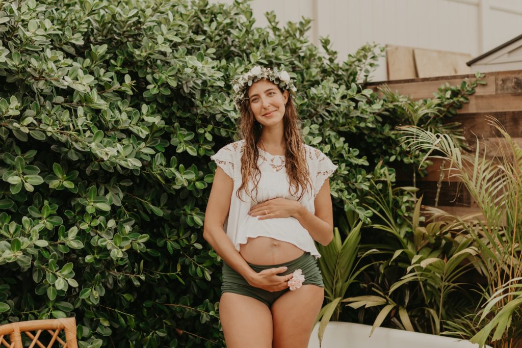 pregnant woman in flower maternity milk bath with haku lei on in austin texas