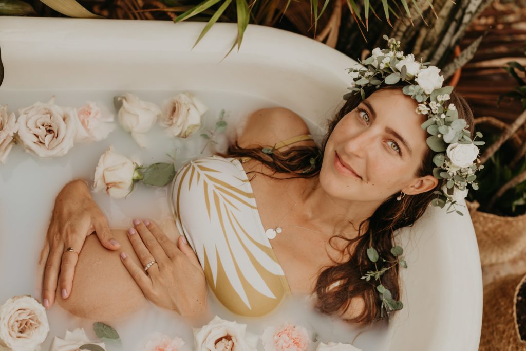 pregnant woman in flower maternity milk bath with haku lei on in austin texas